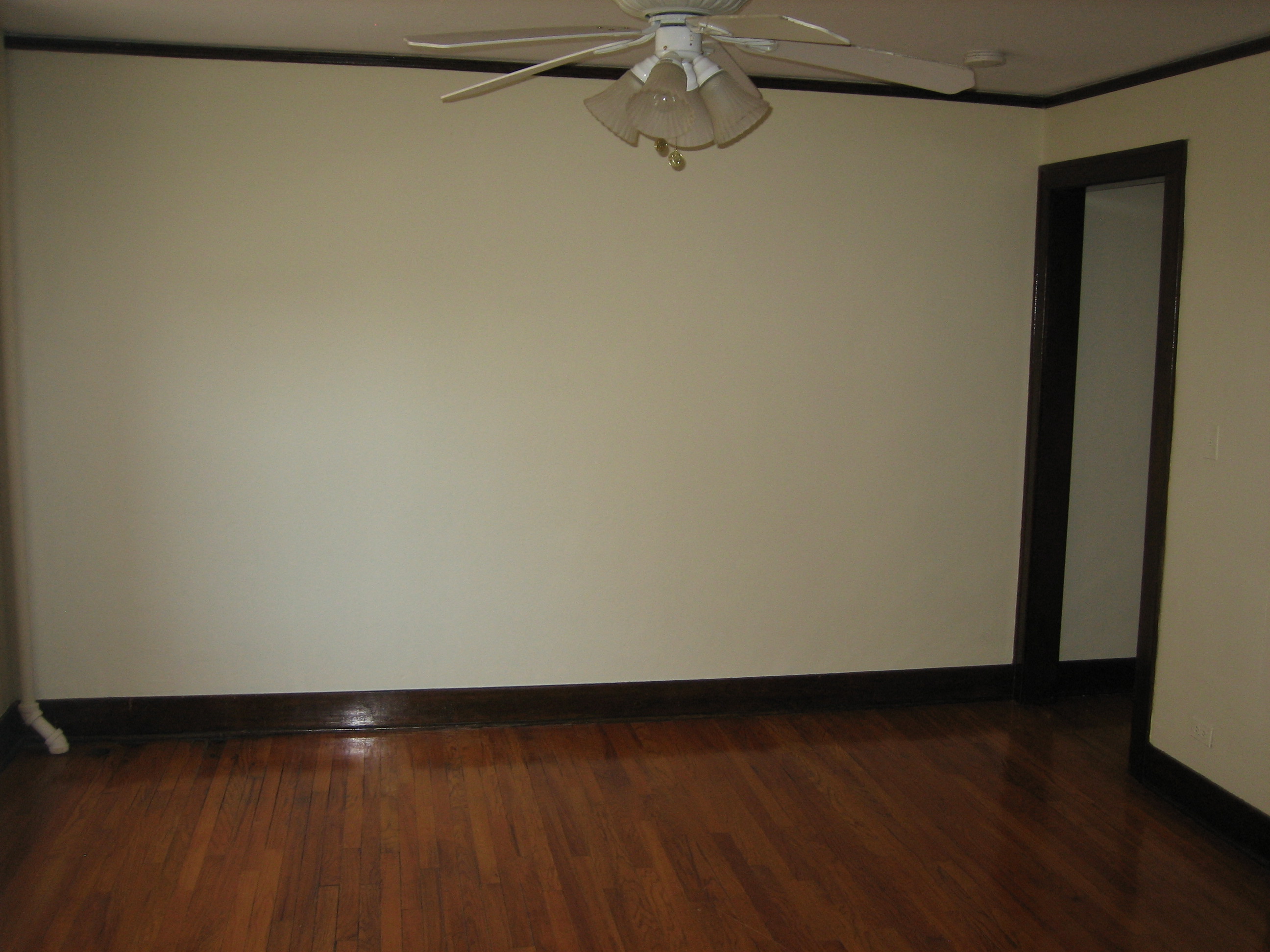 an empty living room with a ceiling fan and wooden floors